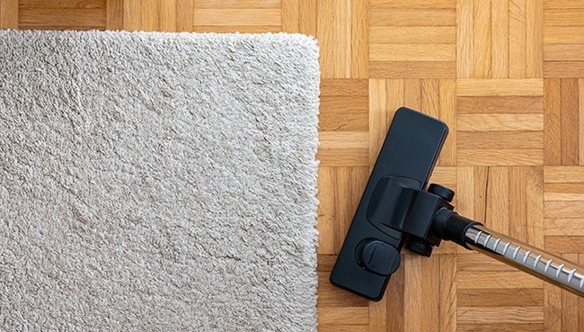 Vacuum cleaner extension on a laminated wooden floor | Dehart Tile